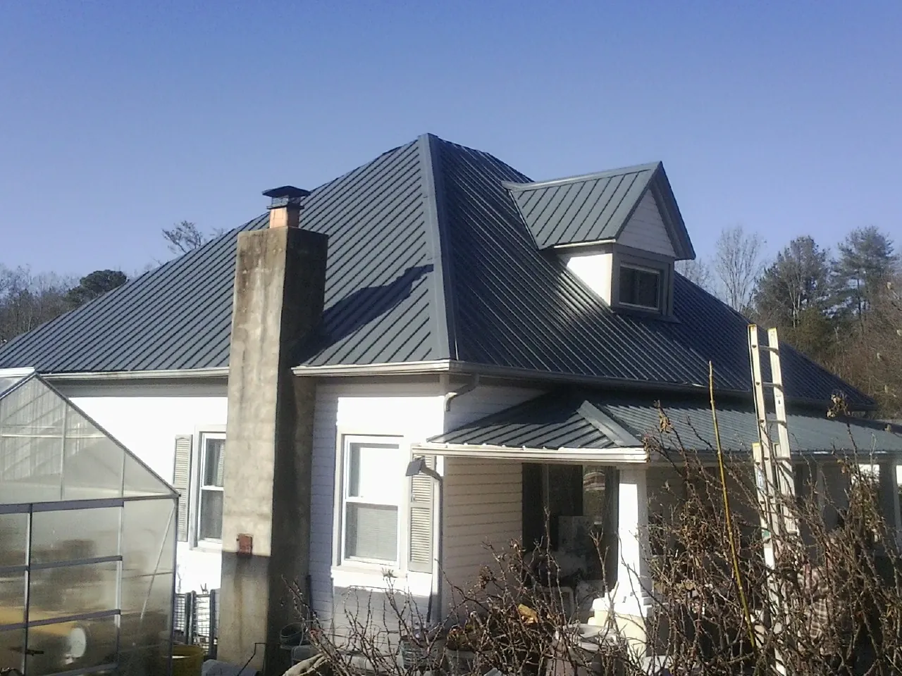 Dark blue standing seam metal roof on a white farmhouse with dormer — Slate & Tile Roof Repair by Roofing Brothers in Reedsport