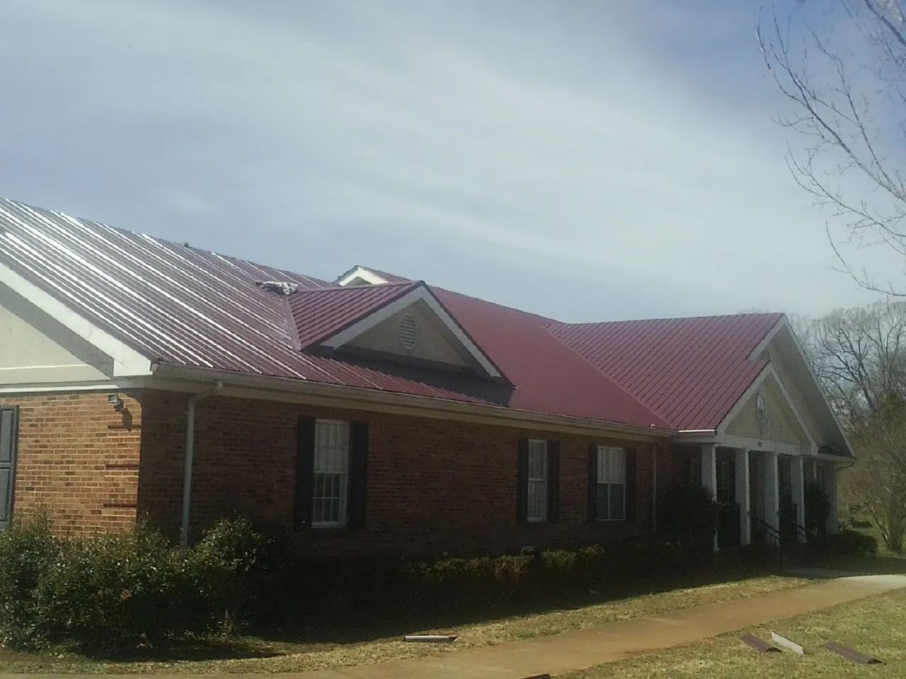 Red metal roof with gabled entries on a long brick building in Reedsport