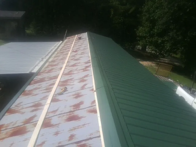 Old rusted panels beside newly installed green metal roofing — Wind Damage Roof Repair by Roofing Brothers in Reedsport