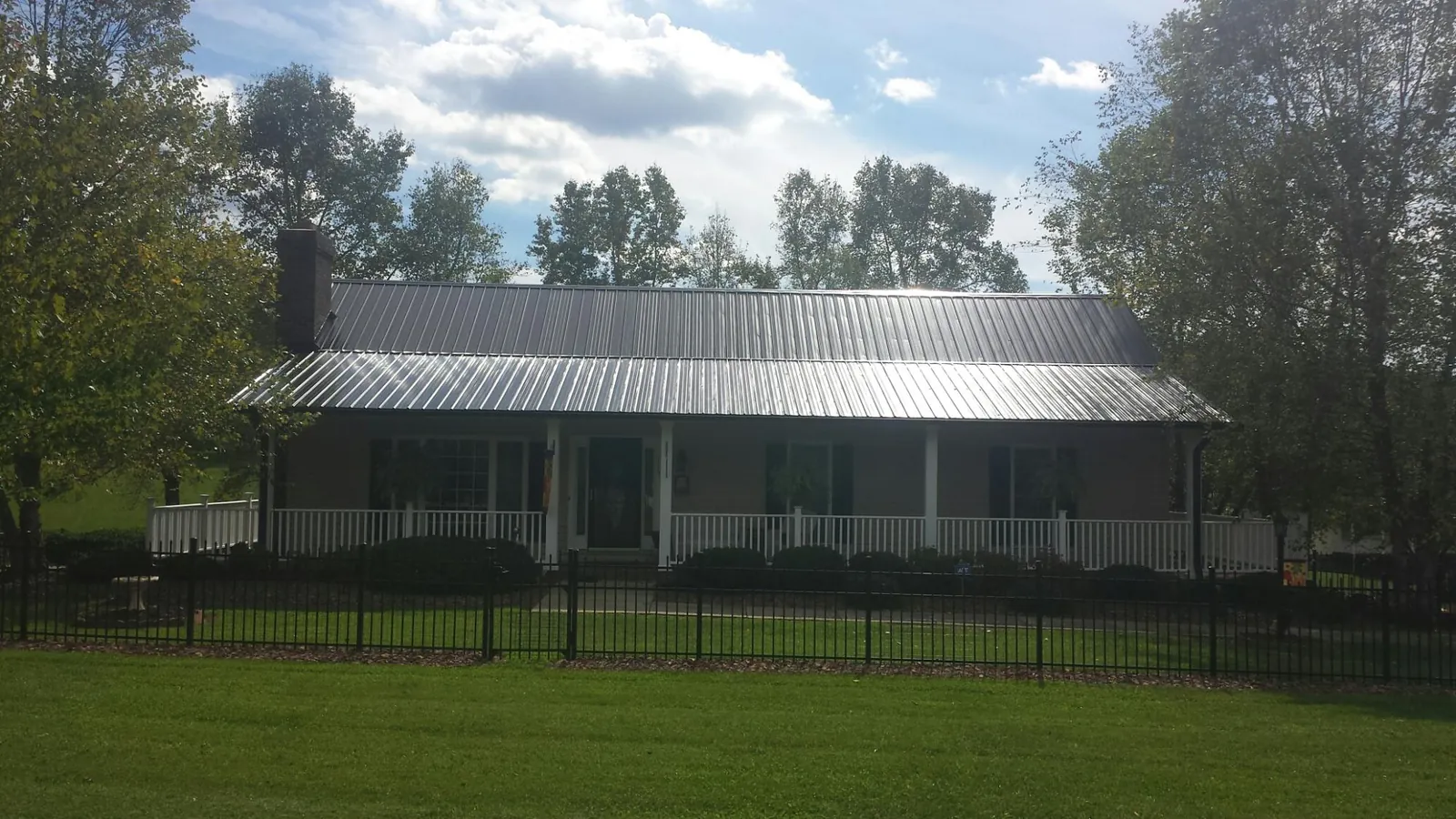 Gray metal roof on a brick ranch with a full width front porch — Gutter Guard Installation work by our crew in Reedsport