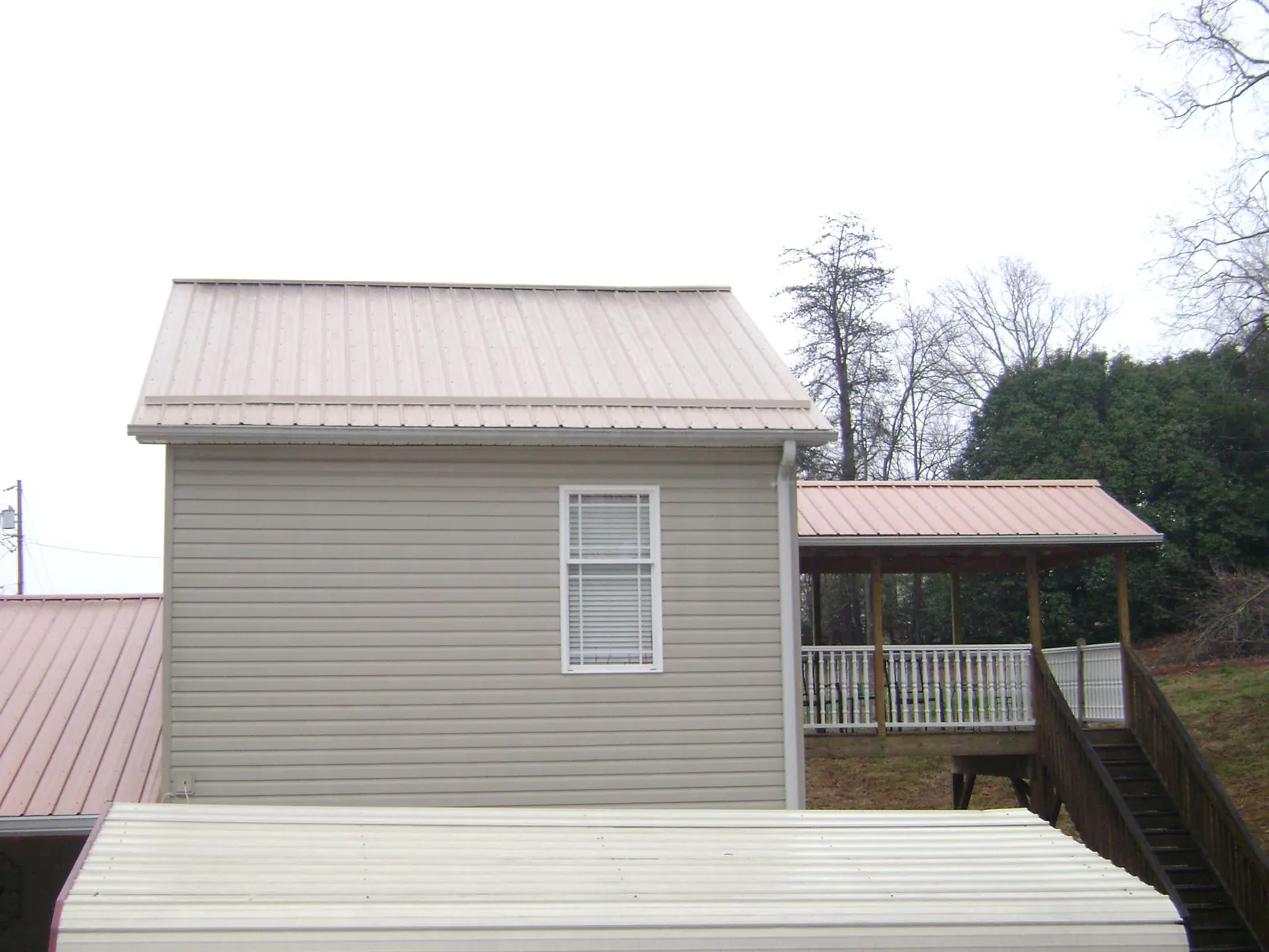 Tan metal roofs on a two story addition and attached porch, from a Roof Replacement job in Reedsport