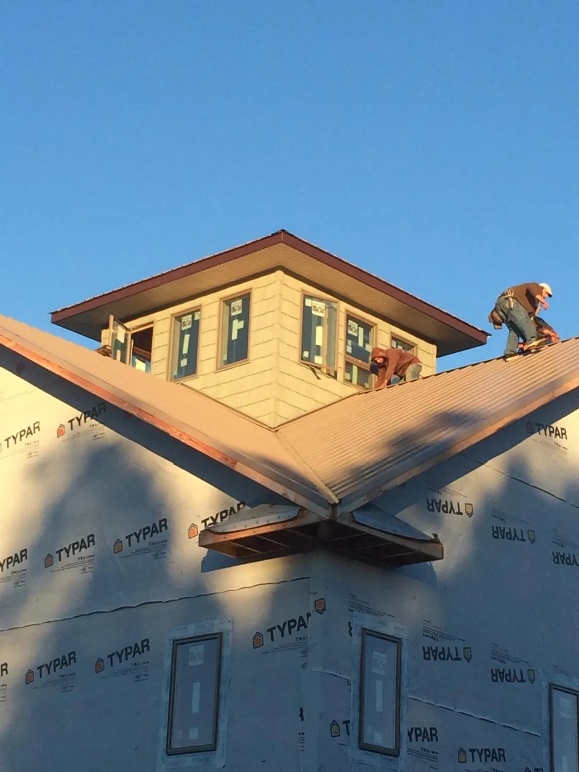 Roofers working around a rooftop cupola on a new metal roof at sunset — Roof Waterproofing in Reedsport by Roofing Brothers